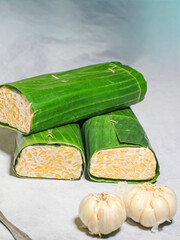 Tempeh wrapped in banana leaves with a marble background. Tempeh is a traditional Indonesian food made from soybeans. It is beneficial for health.