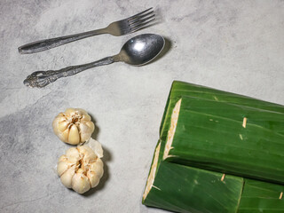 Tempeh wrapped in banana leaves with a marble background. Tempeh is a traditional Indonesian food made from soybeans. It is beneficial for health.