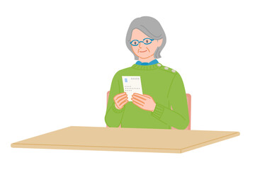 Senior woman reading postcard with both hands at desk