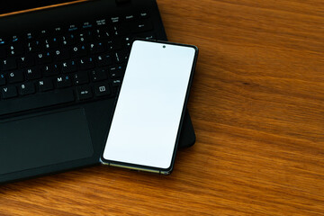 Smartphone Mockup with Blank White Screen on Laptop Keyboard, Modern Workspace with Smartphone Blank Screen and Computer Keyboard