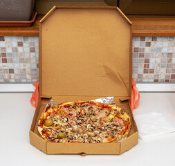 Open cardboard box with baked pizza inside
