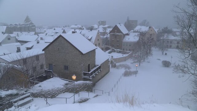 Snowfall over Visby old town seen from hilltop viewpoint, winter pan, Gotland
