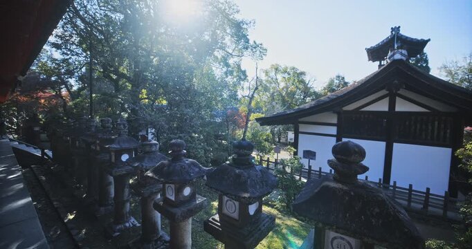 Slow tracking shot alongside line of stone Japanese lanterns near old village