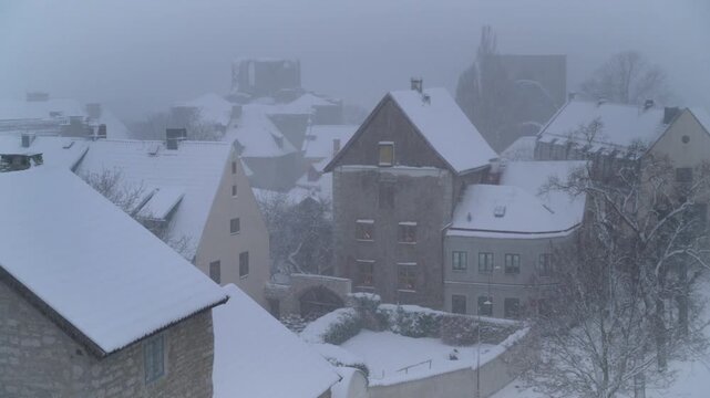 Snow-covered historic buildings in Visby Old Town during winter snowfall (pan), Gotland