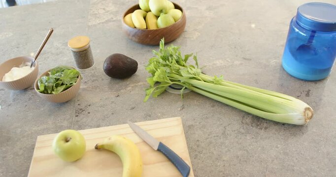 Camera is slowly panning while celery is staying centered on countertop, revealing prep ingredients
