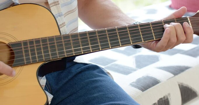 Man is starting right strum, shifting left and picking cutaway guitar by window, performing song