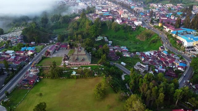 Aerial view of Berastagi town shrouded in thick morning mist and fog with mountain landscape, North Sumatra, Indonesia
