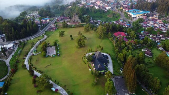 Aerial view of Berastagi town shrouded in thick morning mist and fog with mountain landscape, North Sumatra, Indonesia