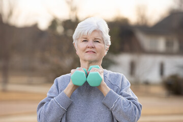 Smiling senior woman holding dumbbells during fitness routine