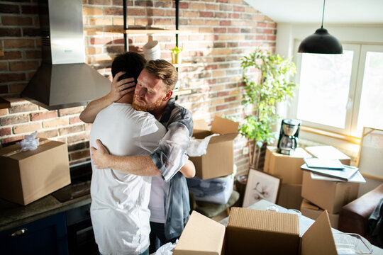 Two men hugging amid moving boxes at home