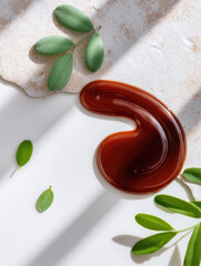 Organic compost tea liquid with rich brown color on white surface surrounded by green leaves and natural sunlight creating fresh and healthy atmosphere