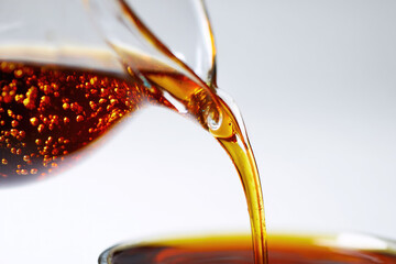 Organic compost tea liquid being poured into glass container, showcasing rich brown color and smooth texture, ideal for natural gardening and plant nourishment