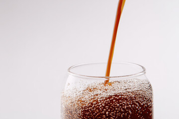 Organic compost tea liquid being poured into clear glass with visible bubbles and refreshing appearance on white background