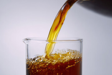Organic compost tea liquid being poured into clear glass beaker with visible bubbles, showcasing rich brown color and healthy gardening solution for plant nourishment