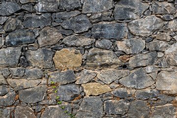Fototapeta premium Granite stone wall texture made of natural rough stones. Detailed rock surface ideal for background, construction, architecture and durability concepts.