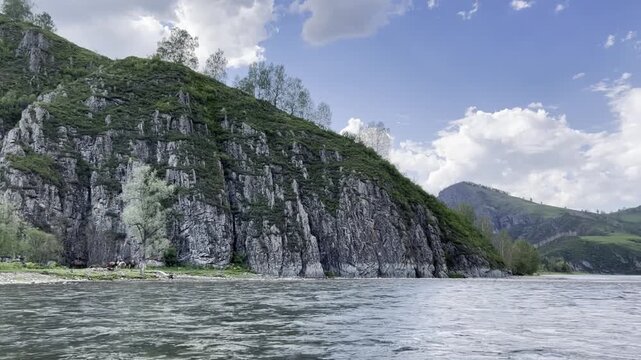 To float down a mountain river along the shore, where a herd of horses grazes.