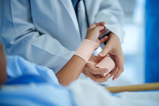 Caring doctor wrapping bandage on child wrist in hospital, gentle support and trust during medical treatment, closeup hands focus, pediatric care, injury recovery, calm mood