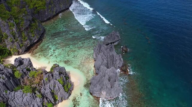 Cinematic drone shot showing a close-up of the secluded Hidden Beach with its white sand and turquoise water tucked between limestone karst cliffs in El Nido, Palawan