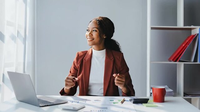 Young African American woman in business attire working at her desk, feeling accomplished