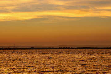 Fototapeta premium Atardecer sobre el mar en La Paz, Baja California Sur, con cielo dorado y horizonte tranquilo. Imagen asociada a turismo, viajes y temporadas de vacaciones en destinos costeros de México.