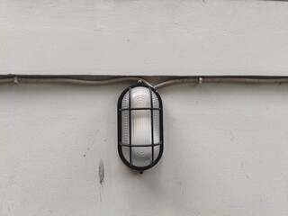 Caged Oval Outdoor Wall Light on a White Building Exterior