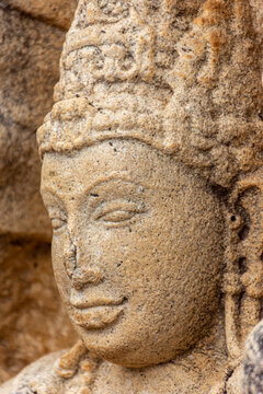 A detailed close-up of the serene face of a stone Muragala guard stone at the Rathna Prasada ruins in the Abhayagiri Monastery, Sri Lanka