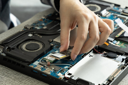 Person Works on Laptop Hardware Repair in a Modern Setting During Daylight Hours