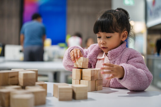 preschool child girl concentrating on building tower with wooden block
