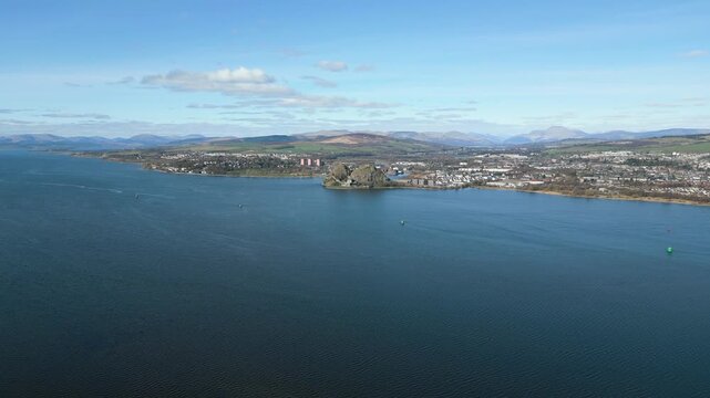 A majestic wide aerial shot flying towards the historic Dumbarton Castle situated on a volcanic plug by the River Clyde in Scotland. Perfect for travel and history documentaries.
