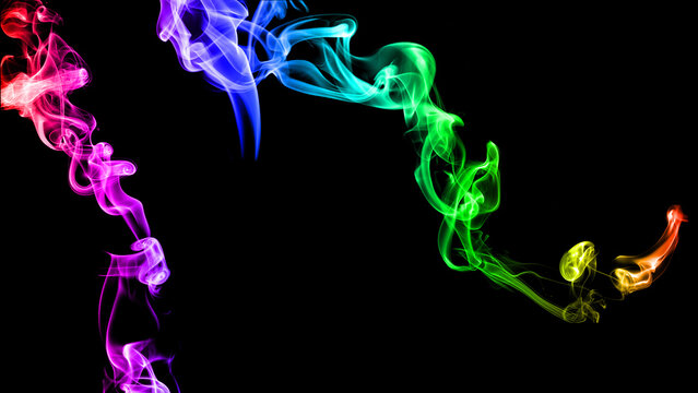 Translucent vibrant coloured smoke whiffs and swirls of aromatic colourful smoke against on a black background.
