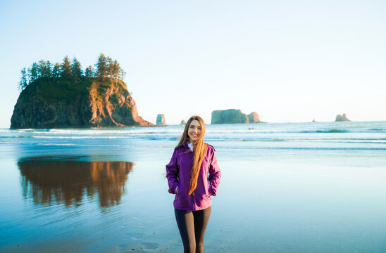 Rear view of a brunette woman on Second Beach during sunset, Olympic National Park, Washington. Outdoor lifestyle, solo travel, peaceful nature and coastal adventure concept.