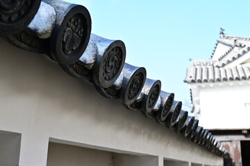 城郭の美：家紋が刻まれた軒丸瓦と白壁のコントラスト