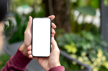 Fototapeta premium Top view close up of a man holding white screen phone in both hands while sits at garden cafe or park