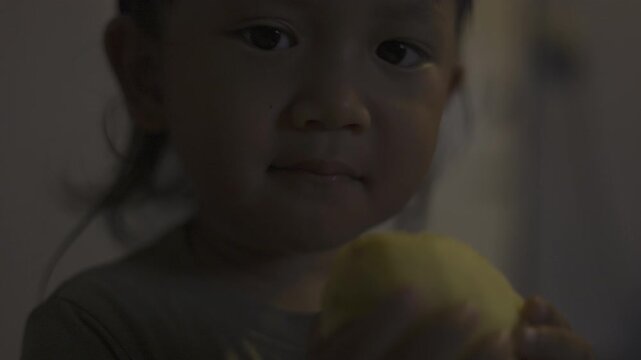 Toddler Holds Peeled Apple Ready To Bite, A cute toddler in a baby suit chews on fingers, wide eyes gleaming under soft light, perfect for family photography shot or playful innocence showcase.