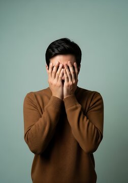 Man covering face with hands in shame
