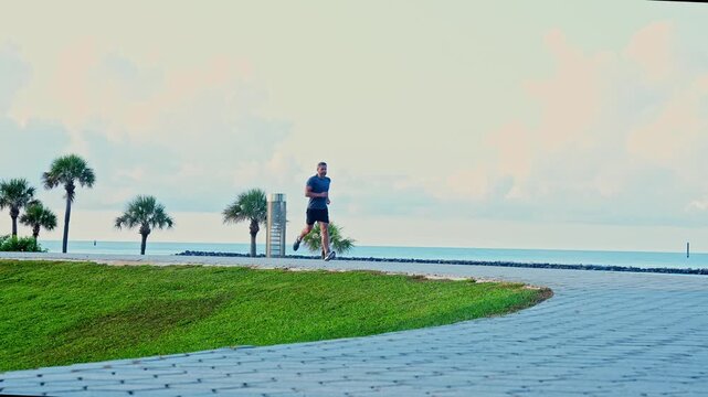 Sportsman jogger running or jogging. Man in sports suit training jogging. Running man, slow motion footage. Morning sport workout jogger run in Miami. The jogger run at sport training