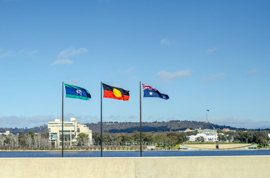 Flags including the Australian national flag, Aboriginal flag, and Australian Capital Territory flag displayed in Canberra, Australia, overlooking Lake Burley Griffin. Symbol of national identity