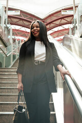Smiling businesswoman ascending escalator in modern station