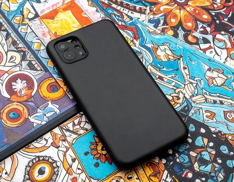 Close-up of a sleek black phone resting on a colorful tiled surface with floral and geometric patterns