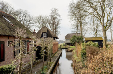 Giethoorn, Netherlands, April 08 2018: A serene canal scene with traditional Dutch houses and well-kept gardens, showcasing the beauty of rural life