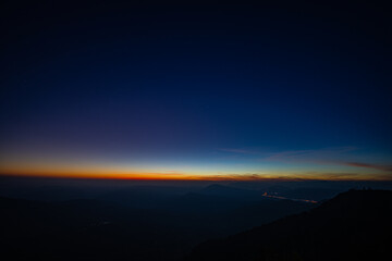 A breathtaking sunset over layered mountain ranges, with warm golden light fading into a deep blue sky, creating a serene and expansive natural landscape ideal for travel and nature themes. © Narong Niemhom