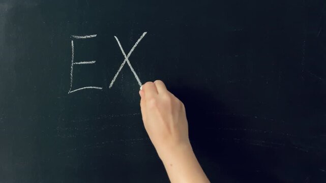 Female hand writing and underlining the word "Exam" in chalk on black slate board. Test evaluation, underlined for emphasis.