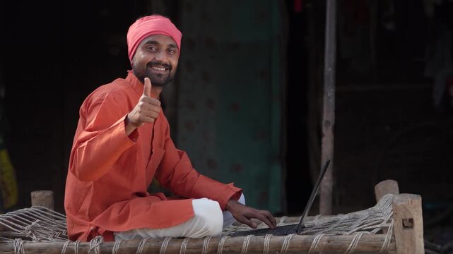 Indian farmer using laptop  and showing thumps up at home