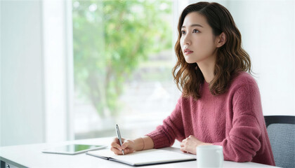 ノートにペンを走らせながら考え事をする真剣な表情の女性