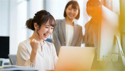 パソコン画面を見て成功を喜びガッツポーズする女性たち