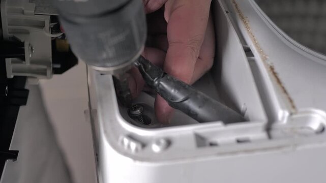 The people use screwdriver to loosen the screw from electric washing machine