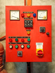 Industrial control panel with buttons and dials mounted on a concrete wall