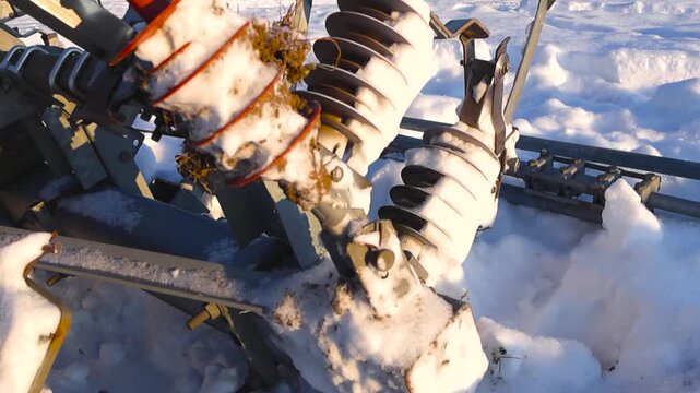 Side angled close view of high voltage railway insulators buried in thick snow, with frost and ice highlighted by warm winter sunlight and visible power cables in the background.