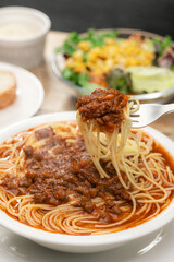 フォークで持ち上げたミートソースのスープパスタ