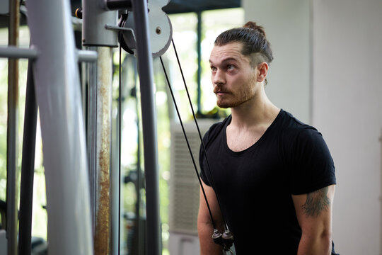 Young sports man workout with rope pushdown in the gym